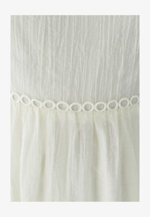 White dress featuring textured fabric with vertical pleats, detailed with a circular lace trim at the waist.