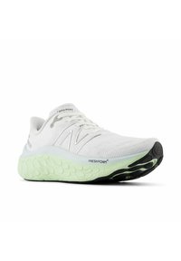 Zapatilla deportiva blanca con un upper de tela texturizada, detalles en plateado y una suela de espuma verde gruesa. Acentos en negro en la suela exterior para mejorar la tracción.