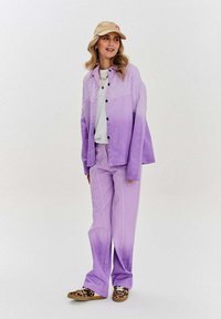 Fialové gradientové přes oversized tričko a odpovídající kalhoty z měkké tkaniny; doplněno bílým tričkem a botami s potiskem zvířat.