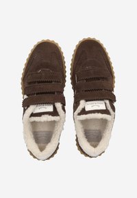 Chaussures en daim marron avec deux bandes velcro, une doublure en fourrure blanche texturée et une semelle en caoutchouc à bord zigzag.