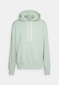Mincová zelená mikina s klokaní kapsou, žebrovanými manžetami a stahovacími šňůrkami. Na hrudi se nachází malé bílé logo Nike. Měkká textilie.