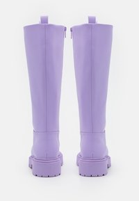 Bottes violettes montantes jusqu'aux genoux avec une texture lisse, dotées d'une fermeture éclair à l'arrière et d'une semelle épaisse avec motif de bande de roulement pour l'adhérence.