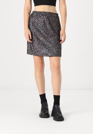 Svart, knelang skjørt med en teksturert, mønstret overflate som har små flerfargede prikker. Elastisk midjebånd. Modell wearing svarte sko og sokker.