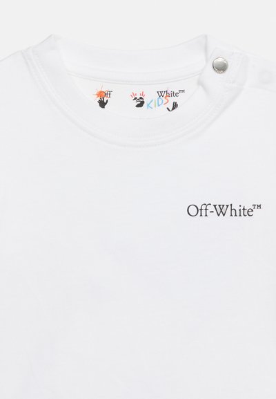 Λευκό παιδικό t-shirt Off-White™ με κουμπί στον ώμο, μαύρο λογότυπο στο στήθος και πολύχρωμα αποτυπώματα χεριών στην εσωτερική ετικέτα γιακά.