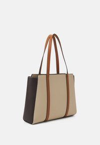 Beige und dunkelbraune Tasche mit braunen Lederhenkeln, rechteckige Form und glatte Textur; verfügt über ein Design mit kontrastierenden Farbpanelen.