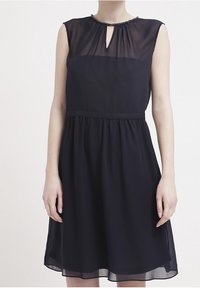 Abito blu navy con tessuto trasparente, scollatura a chiave e dettagli di perline. Vita aderente con gonna svasata che arriva sopra il ginocchio.