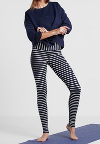 Sudadera navy con cuello redondo y corte holgado, combinada con mallas a rayas en navy y blanco. Textura suave, diseño casual, sin logotipos visibles.