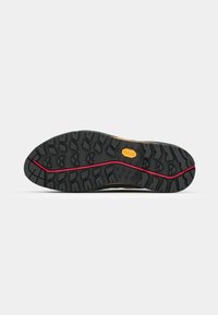 Vibram-Sohle mit tiefen Traktionsprofilen, schwarzes Gummi mit einem roten Akzentstreifen, entworfen für Haltbarkeit und Grip auf verschiedenen Oberflächen.