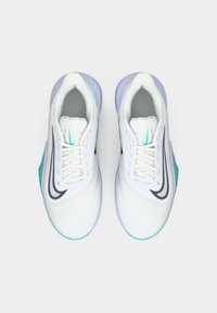 Chaussures de sport blanches avec une tige en mesh, doublure grise, logo Swoosh noir et accents turquoise sur la semelle et le talon. Design à bout rond.