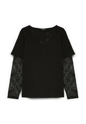 Haut noir à manches longues avec superposition de manches courtes et détail en dentelle florale sur les manches intérieures et le haut de la poitrine.