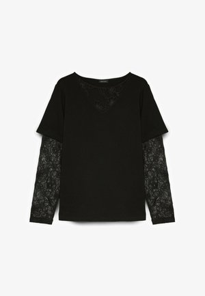 Haut noir à manches longues avec superposition de manches courtes et détail en dentelle florale sur les manches intérieures et le haut de la poitrine.
