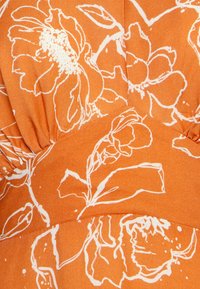 Tecido laranja com padrões florais brancos, com um acabamento texturizado. O design inclui detalhes franzidos e linhas suaves.