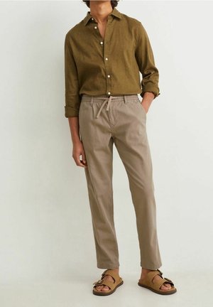 Linen button-up shirt in olive green, paired with tan drawstring trousers and brown sandals, showcasing a relaxed fit and simple design.