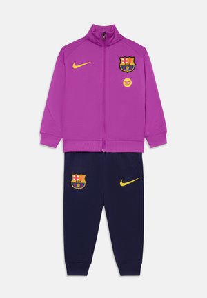Ensemble de sport pour enfants en deux pièces, comprenant une veste zippée violette et un pantalon bleu marine, arborant les logos du FC Barcelone et de Nike en jaune.