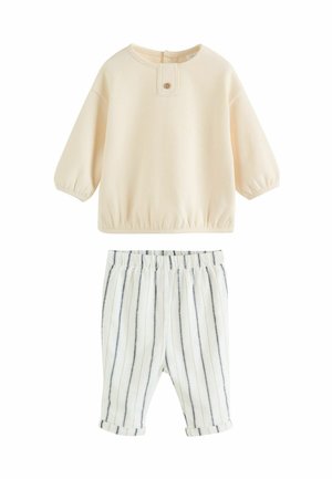 Cream cotton sweatshirt with balloon sleeves and button detail, paired with lightweight striped pants in white and navy blue with an elastic waist.