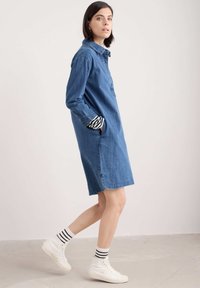 Denimskjortklänning med långa ärmar, bröstficka, sidofickor och längd till mitten av låret. Uppvikta ärmar avslöjar randigt mönster.