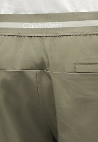 Εσώρουχο Calvin Klein σε ελιά πράσινο, με υφασμάτινη ζώνη μέσης που φέρει το λογότυπο Calvin Klein και μικρή τσέπη στο πίσω μέρος.