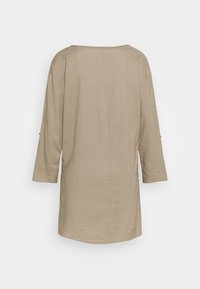 Lichtbeige losse tuniek met driekwart mouwen en een brede halslijn, gemaakt van zachte stof met een gladde textuur.