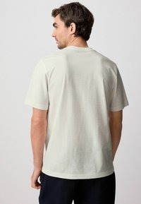 Lys grå kortærmet t-shirt med et subtilt stribet mønster, rund halsudskæring og en afslappet pasform. Materialet ser blødt og letvægtsud.