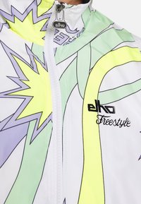 Biała kurtka wiatrówka z kolorowymi geometrycznymi wzorami w kolorach żółtym, zielonym i fioletowym. Posiada zamek błyskawiczny z przodu oraz logo "elko Freestyle".