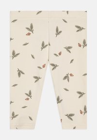 Cremefargede leggings med et heltrykk av grønne furugreiner og brune furukongler, laget av myk og elastisk stoff.