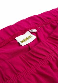 Tessuto fucsia con vita elasticizzata; presenta un'etichetta del marchio "PEANUTS". Materiale in cotone testurizzato e liscio, con dettagli arricciati.