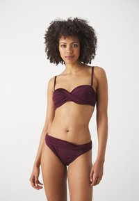 Mauve bikini set with a twisted top design. Material appears smooth, fitted with thin straps and a low-rise bottom featuring a draped accent.