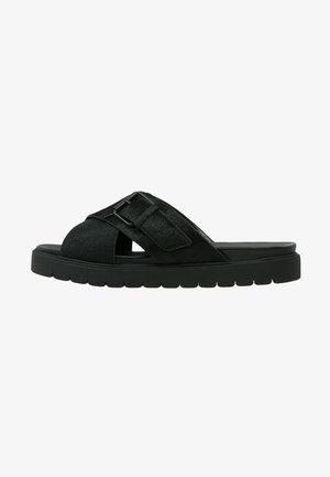 Czarny sandał typu slip-on z grubą podeszwą i szerokimi, skrzyżowanymi paskami z regulowaną klamrą na górze.