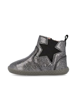 Botines de tobillo plateados con purpurina, con un acento en forma de estrella negra, panel lateral elástico y suela de goma gris con pequeñas protuberancias para tracción.