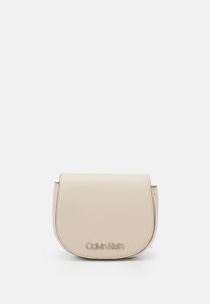 Beige kožená crossbody taška, zaoblený klopový design, embosované logo na přední straně, hladká textura, stříbrné detaily.