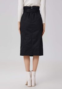 Jupe midi noire avec une taille haute ceinturée, texture lisse et design ajusté. Possède une fente à l'arrière pour plus de mouvement.