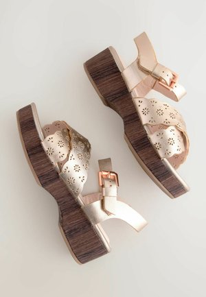 Guld syntetiske lædersandaler med blomstermotiver, træblok hæle og justerbare spænder. Har en glat overdel og tekstureret sål.