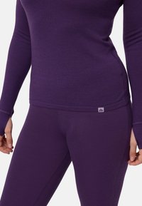 Lila langärmeliges Oberteil und passende Leggings aus weichem, dehnbarem Material. Verfügt über einen figurbetonten Schnitt mit Daumenlöchern und kleinem Logodetail.