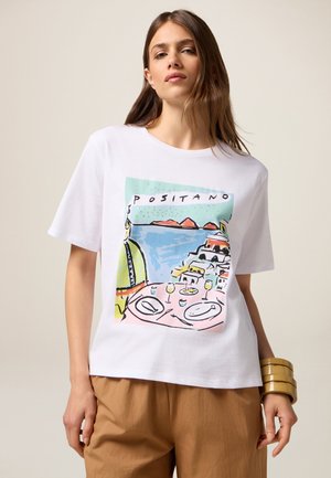 T-shirt bianco in cotone con una grafica colorata di Positano che presenta una scena costiera, un'apparecchiatura da tavola e motivi astratti. Vestibilità rilassata, maniche corte.
