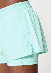 Calções atléticos de um verde menta claro com uma cintura de malha respirável, apresentando um bolso lateral, bainha repartida e uma discrição de logótipo.