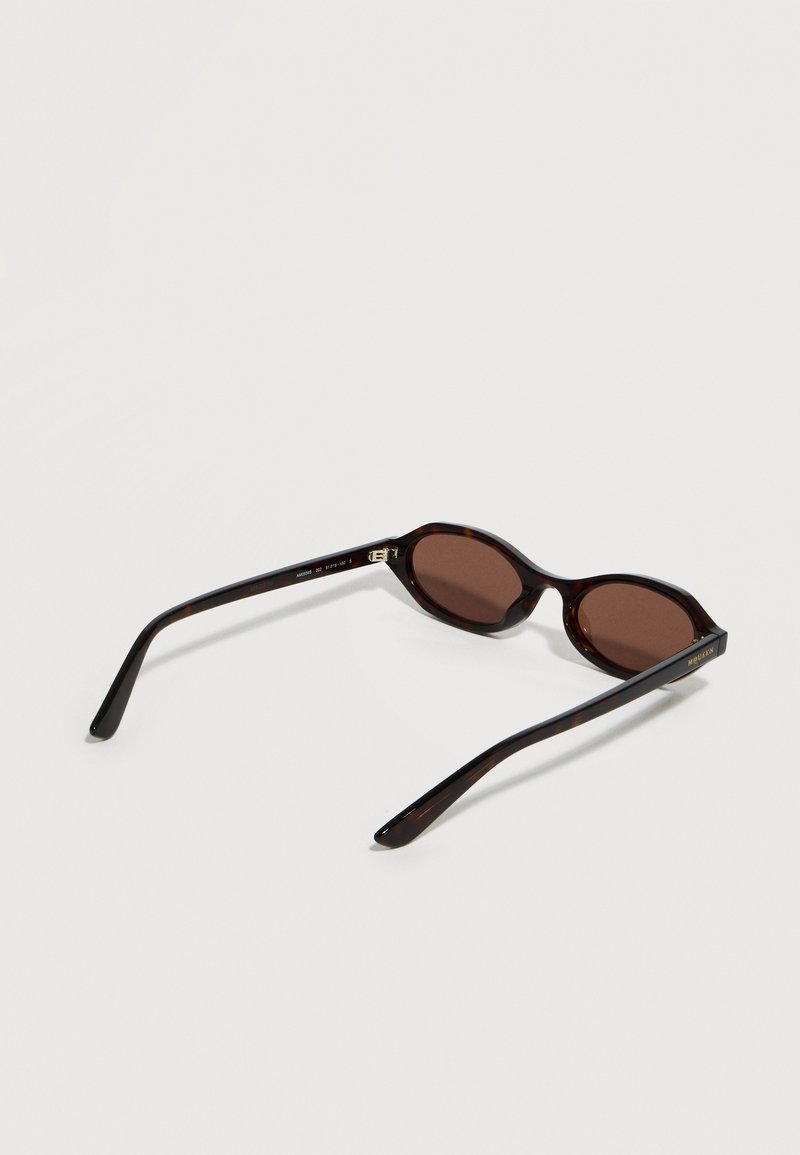 Schildpatt-förmige ovale Sonnenbrille mit dunkelbraunen Gläsern und schlanken Bügeln, die offen auf einer hellen Oberfläche liegen.