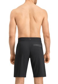 Schwarze Sportshorts aus leichtem Material. Zu den Merkmalen gehören eine Reißverschlusstasche auf der Rückseite und ein enger Bauchbund.
