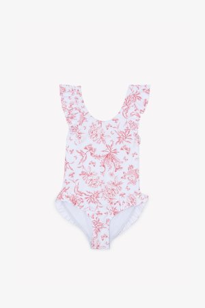 Maillot de bain une pièce blanc avec imprimé floral rouge. Comprend des bretelles à volants et une bordure à volants au niveau des ouvertures des jambes. Matière douce.