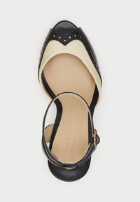 Svart och krämfärgad öppen tå-sko med en vävd överdel, scalloped design, justerbart ankelsnöre och släta läderdetaljer.