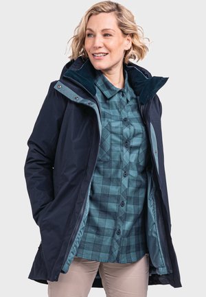 Navy waterproof jacket with zipper and snap closures, teal interior, adjustable hood, and a blue-green checked shirt underneath.
