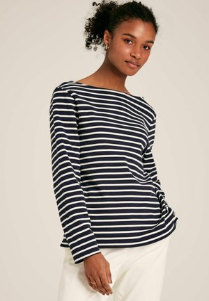 Gestreiftes langärmliges Shirt in Marineblau und Weiß mit einem Bootsausschnitt. Weicher Stoff mit lockerem Schnitt und leichtem Fall, kombiniert mit hellen Hosen.