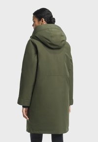 Parka vert olive avec capuche, au design simple, texture lisse, manches longues, longueur jusqu'à mi-cuisse.