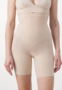 Beige hooggeprijsde shaping shorts gemaakt van een soepele, rekbare stof. Heeft een aansluitend ontwerp en naadloze zijkanten voor een gestroomlijnde uitstraling.