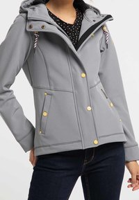 Šedá softshellová bunda s kapucí, zlatými knoflíky a pruhovanou šňůrkou. Obsahuje dvě boční kapsy a přiléhavý střih.