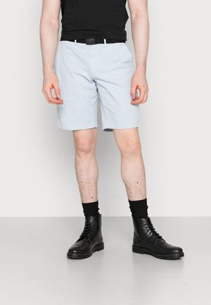 Lyseblå shorts med flad front og sort bælte. Brugt med sorte knæstrømper og sorte snørebåndsstøvler.