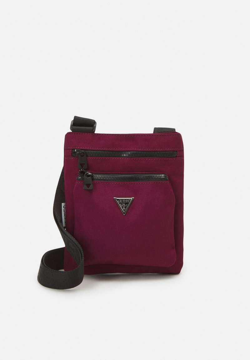 Petit sac bandoulière rectangulaire bordeaux avec deux poches zippées noires et une sangle noire réglable, avec un logo triangulaire Guess.