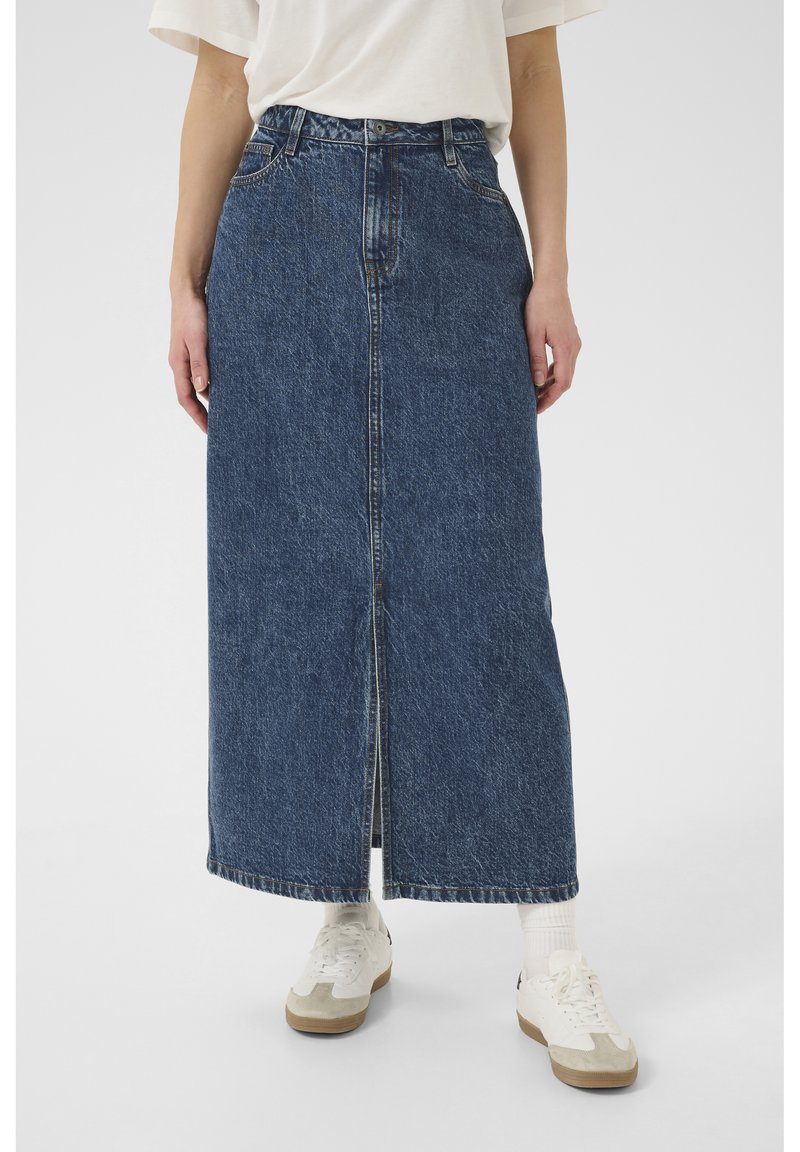 Denim maksi krilo v temno modri barvi s sprednjim razporkom, visokim pasom in petimi žepi. Nosi se z belimi supergami in rebrastimi nogavicami.