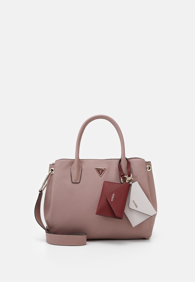 Sac à main en cuir mauve avec double poignées, bandoulière détachable, et portes-cartes Guess rouges et blancs attachés.