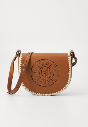 Sac bandoulière en cuir marron avec un design découpé circulaire, une bordure tressée de couleur crème et une sangle réglable.