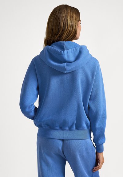 Sweatshirt azul com capuz, feito de tecido texturizado, apresentando punhos e barra canelados, com um ajuste descontraído e acabamento suave.